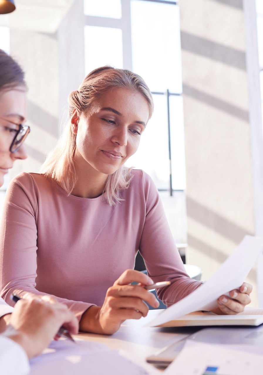 Content pensive young attractive ladies sitting at table in cafe and viewing data while brainstorming about brining product to market